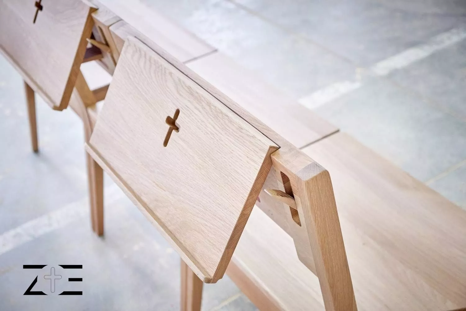 Krzesła kościelne ZOE połączone magnesami w jedną ławkę z logo w lewym dolnym rogu zdjęcia